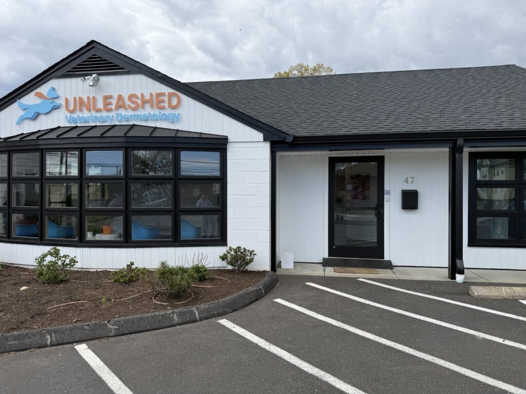 A white building with a black roof and a sign reading Unleashed Veterinary Dermatology